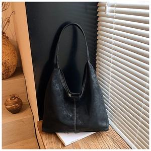Black matte tote bag with contrast stitching on wooden surface near white shutters
