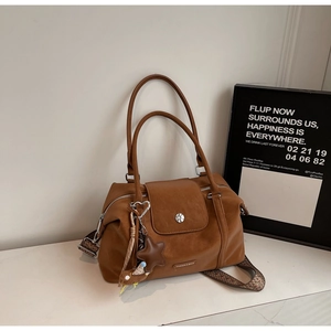 Detail view of caramel brown tote bag with leather star pendant and cartoon charm