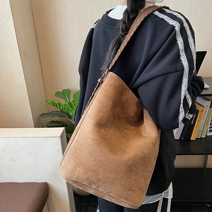 Detail of vintage brown suede tote bag featuring a woven strap and fine stitching