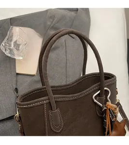 Detailansicht der braunen Ledertasche mit weißen Kontrastnähten und modischem Quastenanhänger