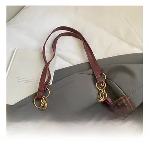 Detail of plaid tote bag with brown leather handle and gold chain links