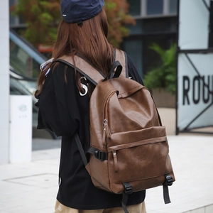 Close-up of brown faux leather texture and zipper pocket on a minimalist backpack