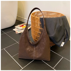 Detail of a dark brown hobo bag in suede texture with white vertical contrast stitching
