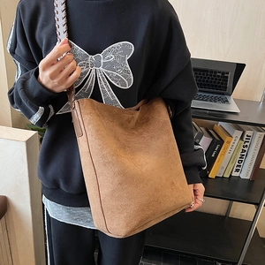 Detail of retro brown suede tote bag featuring a woven strap and spacious bucket design