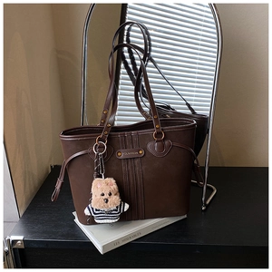 Détail d'un grand sac cabas marron mat avec plaque logo et charmant pendentif de chien