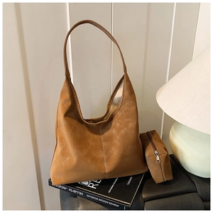 Detailed view of the brown faux suede tote bag and matching small zipper pouch on a black seat