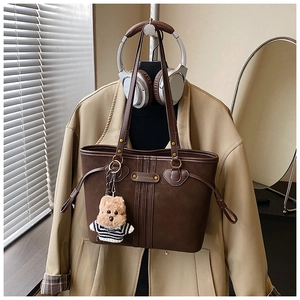 Détail du cabas mat marron foncé avec breloque ours en peluche et clous dorés