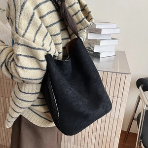 Detail of the black suede tote bag showing woven leather straps and large capacity