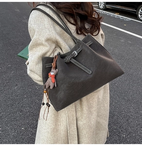 Detail of dark brown tote bag with contrast stitching and cute teddy bear charm