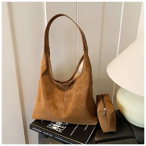Detail of tan tote bag set with contrast stitching leaning on decorative books