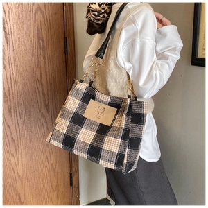 Close-up of vintage plaid wool tote bag featuring a leather bear patch and chain strap