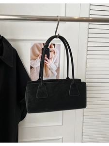 Détail du sac sous le bras noir rectangulaire avec de longues bretelles et un design cousu
