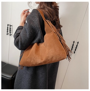 Detail of vintage brown suede hobo bag with long fringes and bohemian style strap