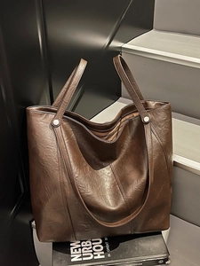 Grande borsa tote moderna marrone scuro in pelle vintage su sfondo urbano alla moda