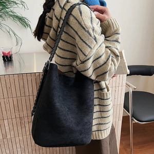 Close-up of black suede bucket bag showing large capacity and woven shoulder strap
