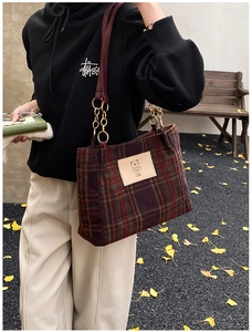 Detail of red plaid wool tote bag with vintage bear patch and gold chain strap