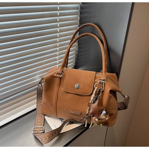 Close-up of retro brown leather tote with geometric strap and cute bear charm
