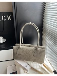 Détail d'un sac sous le bras vintage allongé avec texture mate posé sur des livres au soleil