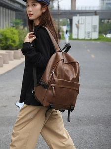 Minimalist large capacity dark brown soft leather backpack worn by a model in city street