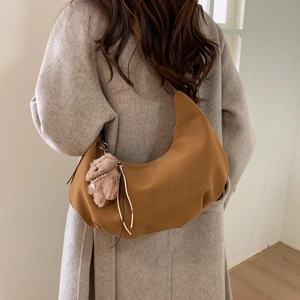 Detail of caramel hobo bag with a cute plush bear charm on a grey wool coat back view