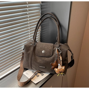 Close-up of vintage brown tote bag with metal logo and woven strap on a window sill