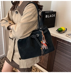 Close-up of black tote bag with white contrast stitching and cute teddy bear pendant