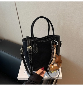 Détail du sac cabas noir avec coutures blanches, breloque ours et bandoulière réglable