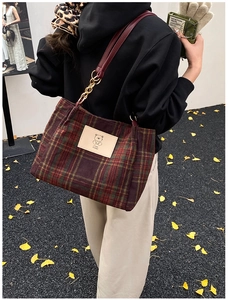 Close-up of red and green plaid wool tote bag with cartoon bear patch and chain strap