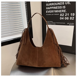 Macro detail of a brown frosted suede shoulder bag featuring stylish fringe tassels on its side
