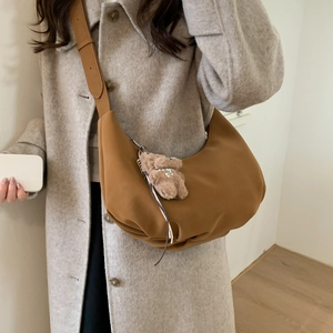 Caramel crescent shoulder bag with bear charm detail shown on a grey wool coat model