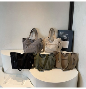 Multi-color nylon tote bags displayed on white pedestals in five earthy tones
