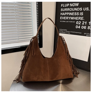 Detail shot of vintage brown suede hobo bag featuring long stylish tassels and wide strap