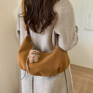 Brown crescent bag detail showing soft texture and cute teddy bear charm on shoulder strap