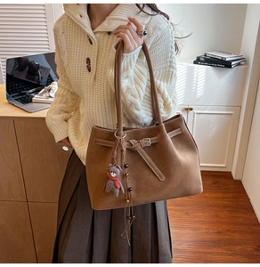Detail of dark brown matte tote bag with decorative buckle and cute bear charm