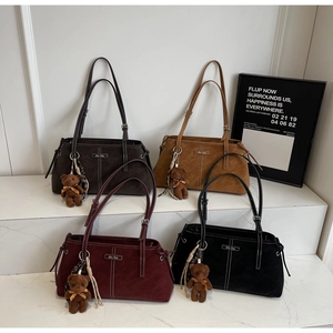 Detail view of four suede tote bags in various colors with contrast stitching and bear charms