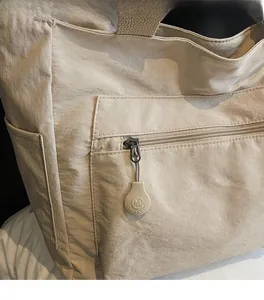 Detail view of the beige casual tote bag featuring a zipped front pocket and smooth fabric