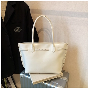 Detail of off-white tote bag with silver studs and long handle on silver luggage