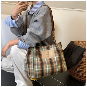 Detail of plaid wool tote bag with cartoon bear leather patch and chain shoulder strap