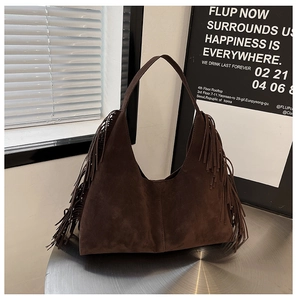 Detailed view of vintage dark brown suede hobo bag with fringe decor on a metal table