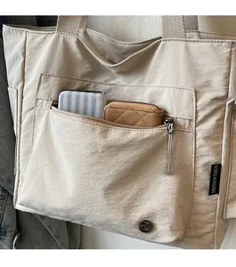 Close-up of beige nylon tote bag with functional front zipper pocket for card holders