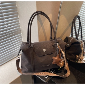 Detail of vintage matte tote bag showing ethnic woven strap and metal logo plaque