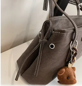 Detail view of dark brown frosted leather tote bag with contrast stitching and bow tie