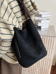 Retro black suede tote bag with woven leather edges shown on model in side view