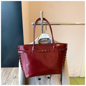 Detailed macro view of burgundy high-gloss leather tote with stylish metal rivet decorations