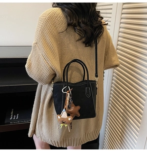 Détail du sac seau noir mat avec surpiqûres blanches et breloque ours en peluche mignonne