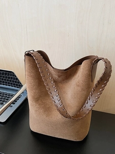 Brown faux suede bucket tote bag featuring a decorative woven wide shoulder strap