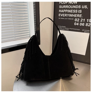 Close-up of black suede hobo bag with fringe details and bohemian shoulder strap