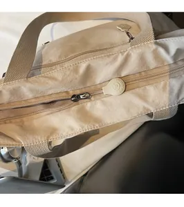 Detail of smooth metal zipper and logo puller on large khaki nylon tote bag