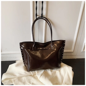 Detail of a deep brown glossy tote bag with silver rivets on a minimalist background