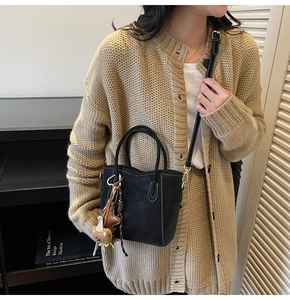 Détail du sac seau noir mat avec surpiqûres blanches et pendentif ours mignon